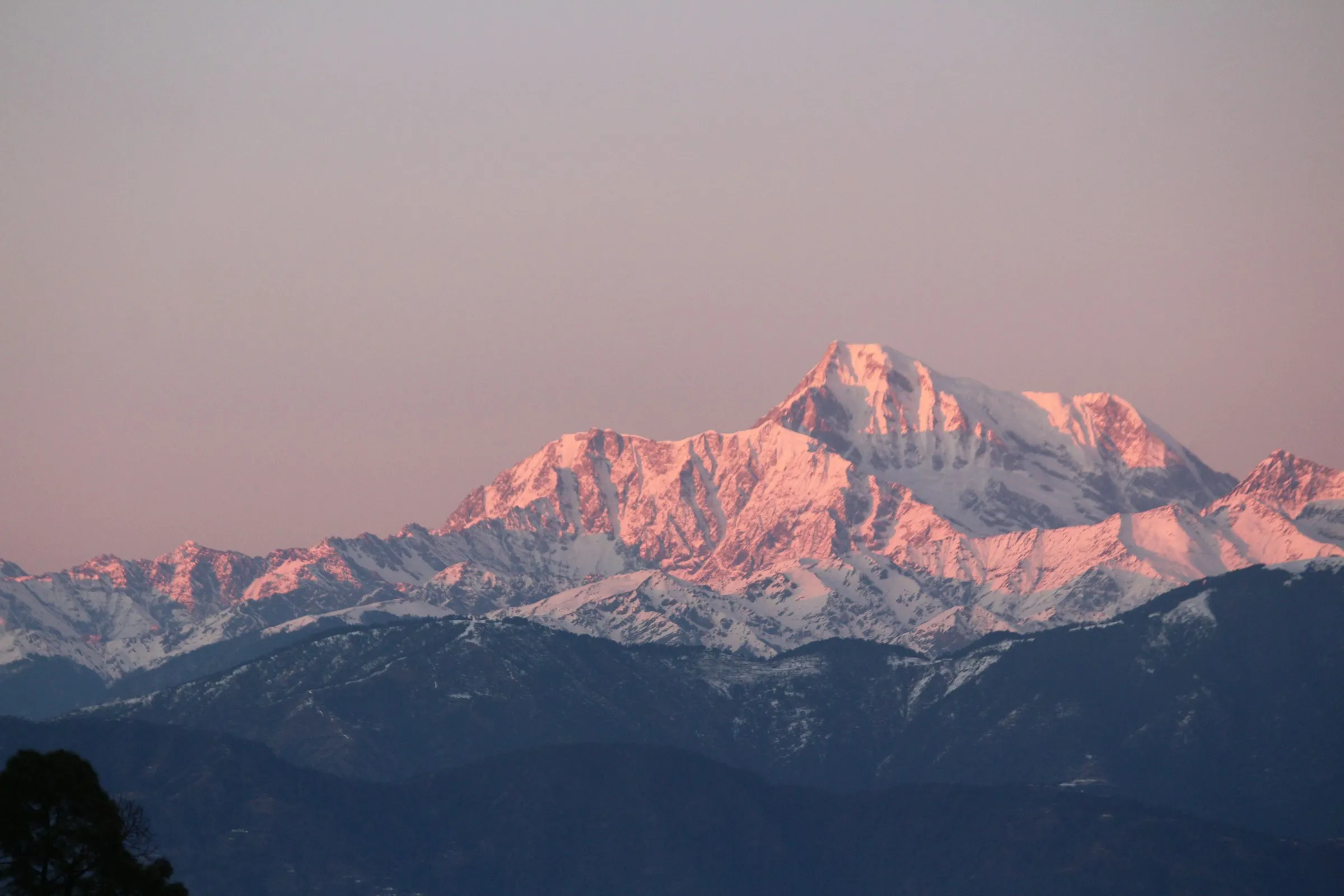 Pink alpenglow lighting a distant Himalayan peak at dusk