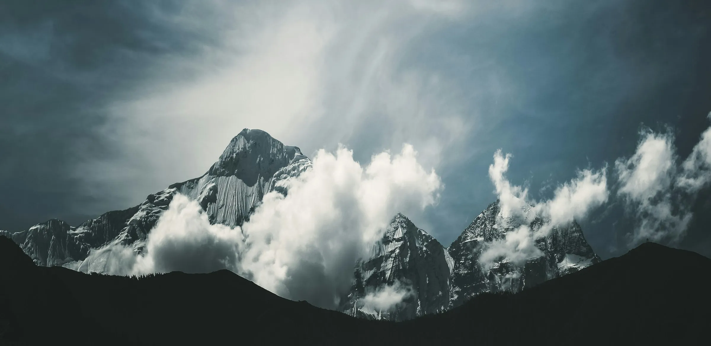 A storm-lit Himalayan peak wreathed in swirling clouds